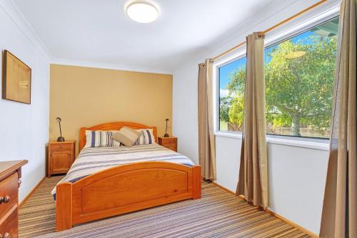 a bedroom with a bed and a large window at Berry by The Bay in Vincentia