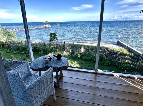 un gato sentado en una mesa en un porche con vistas al océano en Sanctum Una Una Eco Dive Resort en Pulau Unauna