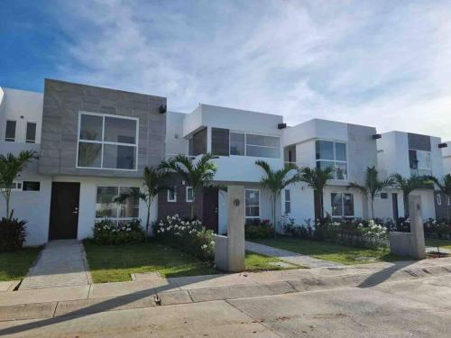 duży biały dom z palmami przed nim w obiekcie Hermosa casa en Acapulco con club de Playa. w Acapulco