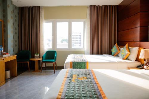 a hotel room with two beds and a desk at Silk Hotel near Tan Son Nhat Airport in Ho Chi Minh City