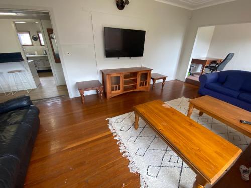 a living room with a couch and a table and a tv at Normandie Wollongong in Wollongong