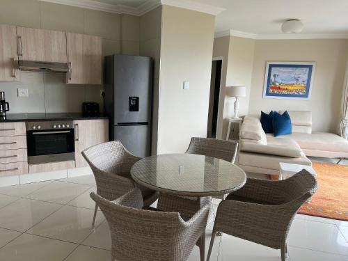 een keuken en een woonkamer met een tafel en stoelen bij Oceanway Self-catering Accommodation in Gonubie
