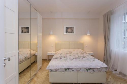 een witte slaapkamer met 2 bedden en een spiegel bij Graf Ignatiev Central Apartment in Sofia