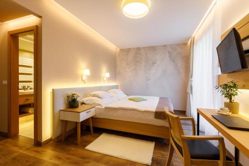 a small bedroom with a bed and a desk and a desk at Hotel Historia Malomkert in Veszprém