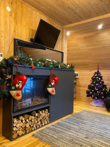 a living room with a fireplace with christmas socks and a christmas tree at Pirts "Spārītes" in Geraņimova