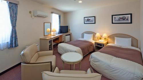 um quarto de hotel com duas camas e uma secretária em Hotel Sato em Shinhidaka