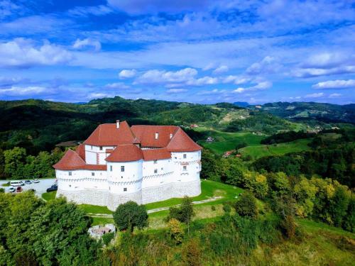 a large white castle with a red roof on a hill at Apartman President in Krapinske Toplice