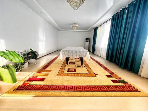 a dining room with a table on a rug at Guesthouse GreatHome in Karakol