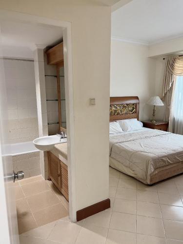 a bedroom with a bed and a sink and a tub at Batavia apartements in Jakarta
