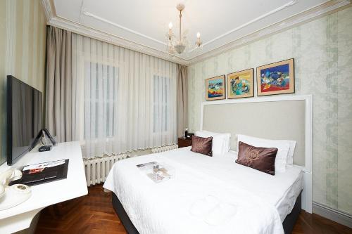 a bedroom with a large white bed and a television at Faik Pasha Hotels Special Category Beyoglu Istanbul in Istanbul