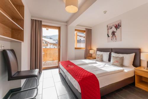 a bedroom with a large bed with a red blanket at AlpenParks Apartments Maria Alm in Maria Alm am Steinernen Meer