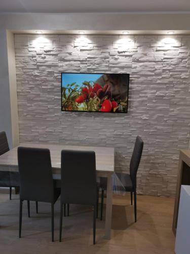 a dining room with a table and a television on a brick wall at Belvedere Tonale in Passo del Tonale