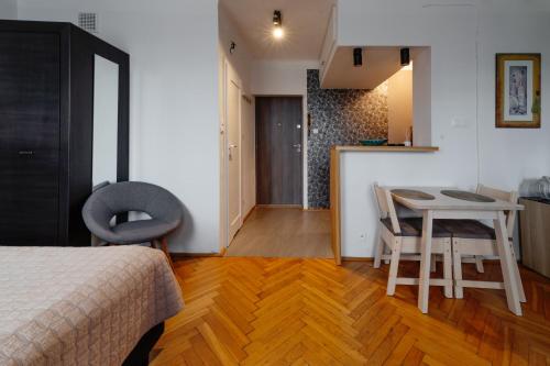 a bedroom with a bed and a table and a kitchen at Kwiatowa Warsaw Apartment in Warsaw