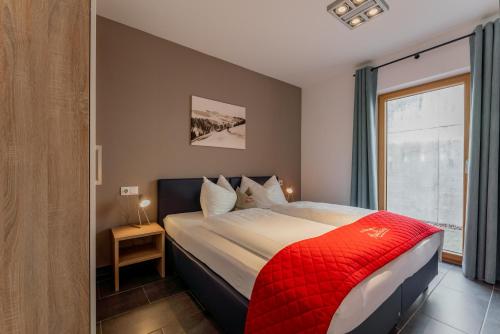 a bedroom with a large bed with a red blanket at AlpenParks Apartments Maria Alm in Maria Alm am Steinernen Meer