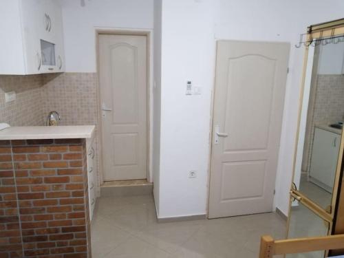 a kitchen with two white doors and a brick wall at Perfect Place 2 - Djenovici in Ðenovići