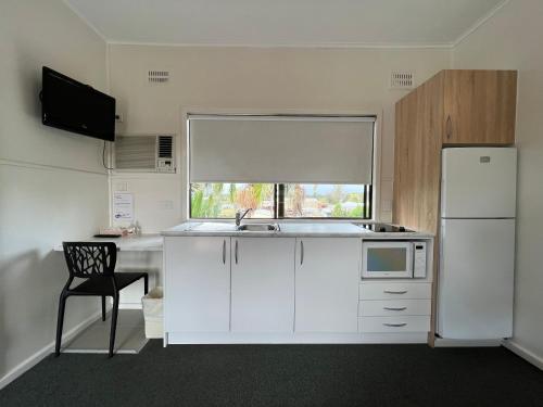 a kitchen with white cabinets and a white refrigerator at Hi-Way Motel Grafton - Contactless in Grafton