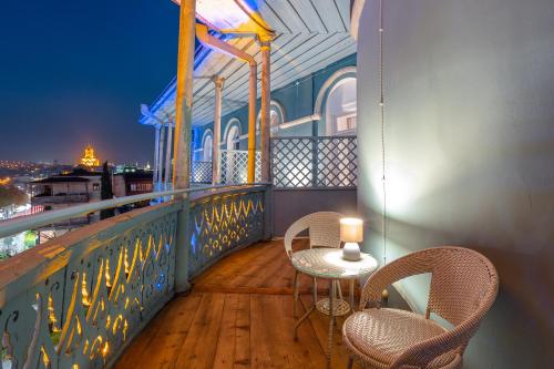 a balcony with two chairs and a table with a candle at Blue Balcony Hotel in Tbilisi City