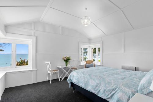 a white bedroom with a bed and a table and chairs at Bayview Bungalow - Nelson Holiday Home in Nelson