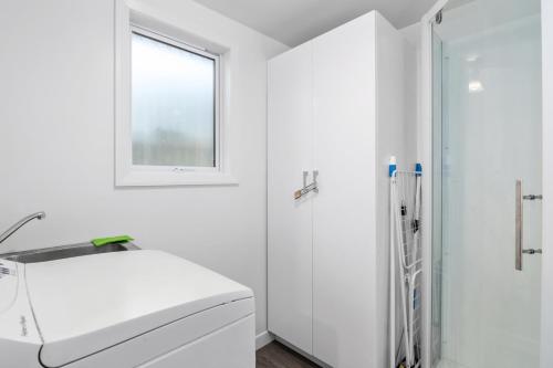 a white bathroom with a shower and a sink at Bayview Bungalow - Nelson Holiday Home in Nelson