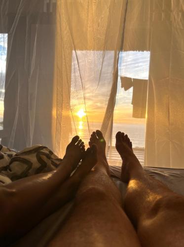 a couple of people laying on a bed with the sun shining through a window at Sanctum Una Una Eco Dive Resort in Pulau Unauna
