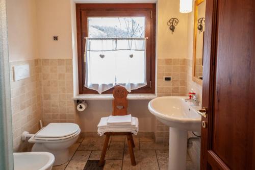 a bathroom with a toilet and a sink and a window at Maison Le Champ B&B Questa casa non è un albergo in La Salle