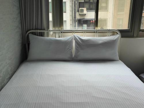 a bed with white pillows in a room with a window at 109台北旅館-台北109青旅 109 Taipei Hotel - Taipei 109 Hostel in Taipei