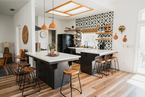 a kitchen with a island and stools in a room at Glamour Mountain Getaway by Casa Oso with views and spa in Oakhurst