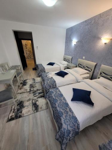 ein Hotelzimmer mit 3 Betten und einem Tisch in der Unterkunft Hotel Dorobanti in Iaşi