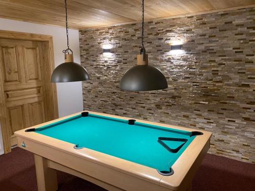 a pool table in a room with two pendant lights at Penzion Pod lesem in Pec pod Sněžkou