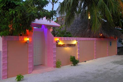 a pink building with a sign that reads happy minute at Rasdhoo Coralville in Rasdu