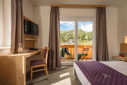 um quarto de hotel com uma cama e uma varanda em Hotel Hierzegger em Tauplitzalm