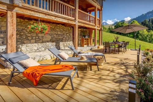 une terrasse en bois avec des chaises et des tables sur une maison dans l'établissement Chalet Argali - OVO Network, au Grand-Bornand