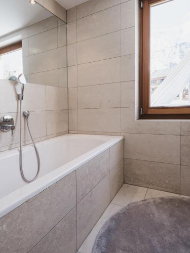 a bathroom with a bath tub and a window at The Crystal VAYA Unique in Obergurgl
