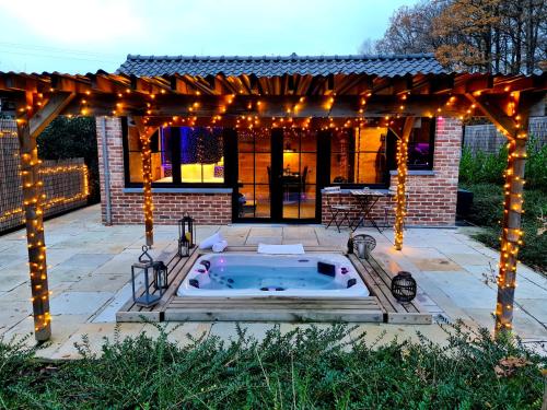 un patio con bañera de hidromasaje bajo una pérgola con luces en Ocove, en Durbuy