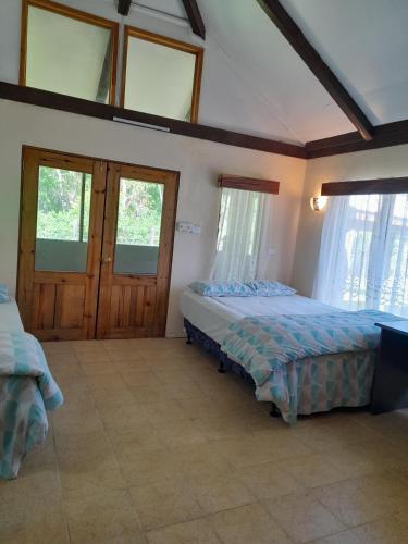 a bedroom with two beds in a room with windows at Fiji Fishing Holiday Bure in Savusavu