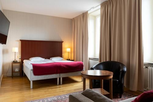 a hotel room with a bed and a table at Hotel Bishops Arms Kristianstad in Kristianstad