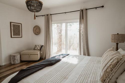 a bedroom with a bed and a chair and a window at Glamour Mountain Getaway by Casa Oso with views and spa in Oakhurst