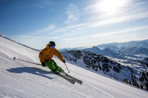 a person is skiing down a snow covered slope at Hotel Hierzegger in Tauplitzalm