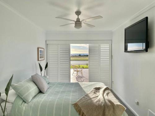 um quarto com uma cama e uma televisão de ecrã plano em The Landing Aldinga Beach Front Private Pool em Aldinga Beach