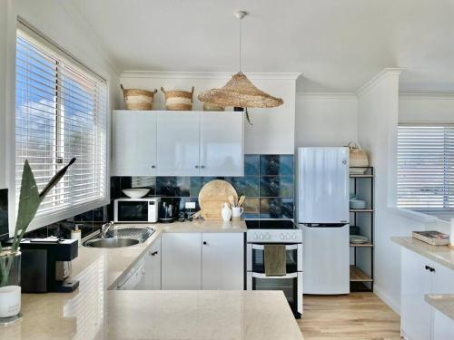 a kitchen with white cabinets and a white refrigerator at The Landing Aldinga Beach Front Private Pool in Aldinga Beach