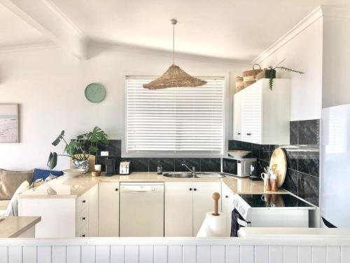uma cozinha com armários brancos e um lavatório em The Landing Aldinga Beach Front Private Pool em Aldinga Beach