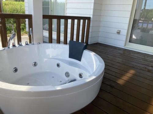 a large white tub in a room with a balcony at 海まで徒歩5分-BBQ バレルサウナ ジャグジー ペットOKの貸切villa in Ichinomiya