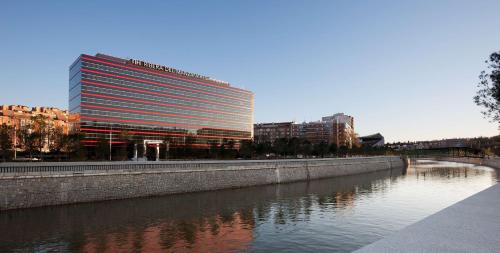 un edificio alto junto a un río con edificios en NH Madrid Ribera del Manzanares, en Madrid