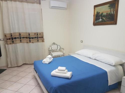 een slaapkamer met een blauw bed en handdoeken bij Just Pompei Holiday House in Scafati