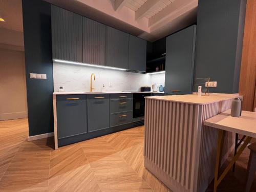 a kitchen with black cabinets and a wooden floor at Grand Apartament in Złotów
