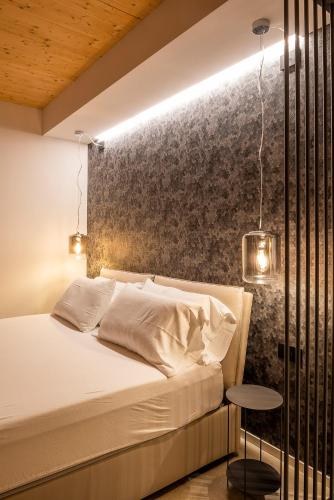 a bedroom with a white bed and a wall at Relais Limonaia - Suites & Garden SPA in Torri del Benaco