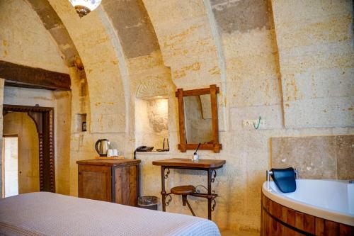 Schlafzimmer mit einem Bett, einem Waschbecken und einer Badewanne in der Unterkunft Karma Suites Cappadocia in Uchisar