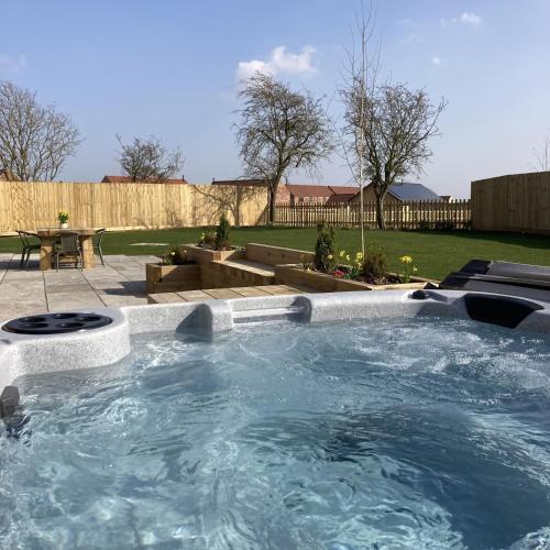 a large hot tub in a yard with a patio at Blue Iris Cottage, Ashlin Farm Barns in Lincoln