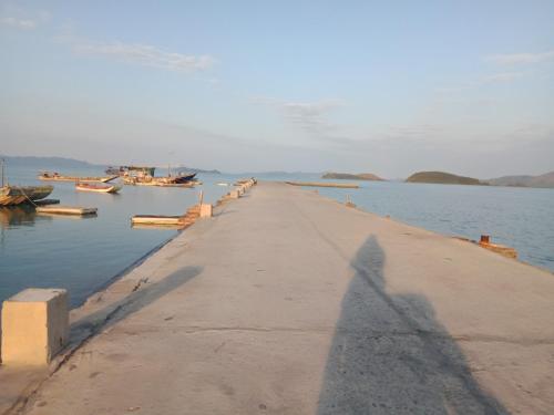 a shadow of a person standing on a dock in the water at Quan Lan Nam Phong Hotel in Quan Lạn