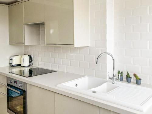 a white kitchen with a sink and a counter at Cosy Apartment in Winchester
